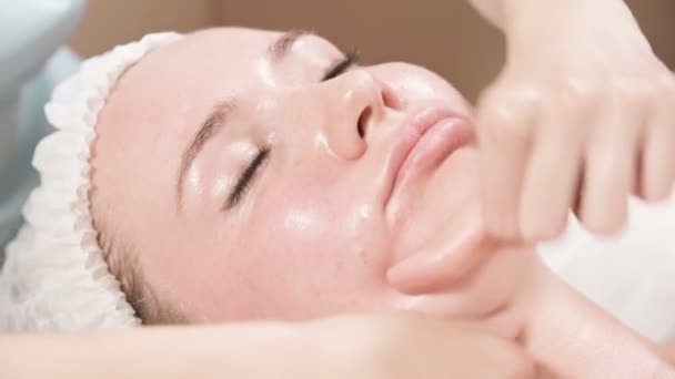 Primer plano Spa masaje facial. Chica terapeuta de masaje profesional hace un masaje facial relajante a un cliente atractivo de un salón de spa — Vídeo de stock