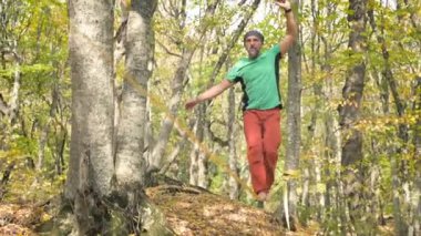 Slackline, spor giyimli sakallı yaşlı bir adam ip üzerinde dengede yürüyor. 50 'li yaşlardaki spor aktiviteleri konsepti