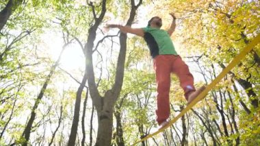 Slackline, spor giyimli sakallı yaşlı bir adam ip üzerinde dengede yürüyor. 50 'li yaşlardaki spor aktiviteleri konsepti