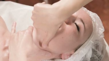 Kapalı Spa yüz masajı. Profesyonel masaj terapisti çekici bir spa salonu müşterisine yüz masajı yapıyor.