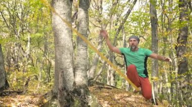 Spor kıyafetleri içinde sakallı, gevşek bir adam ip üzerinde dengede yürüyor. 50 yaşındaki spor aktiviteleri konsepti
