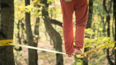 Spor kıyafetleri içinde sakallı, gevşek bir adam ip üzerinde dengede yürüyor. 50 yaşındaki spor aktiviteleri konsepti. Sporcular ayaklarına yakın çekim