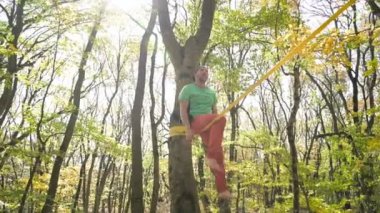 Slackline, spor giyimli sakallı yaşlı bir adam ip üzerinde dengede yürüyor. 50 'li yaşlardaki spor aktiviteleri konsepti