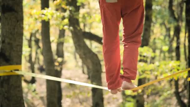 Spor kıyafetleri içinde sakallı, gevşek bir adam ip üzerinde dengede yürüyor. 50 yaşındaki spor aktiviteleri konsepti. Sporcular ayaklarına yakın çekim — Stok video