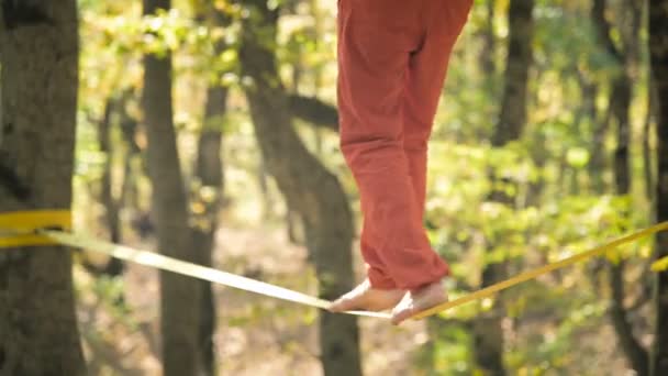 En Slack man åldras med skägg i sportkläder promenader balanserar på slackline. Begreppet idrottsverksamhet vid 50 års ålder. Idrottare fot närbild — Stockvideo