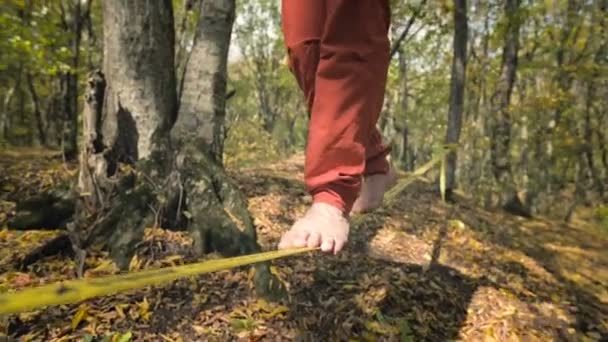 Spor kıyafetleri içinde sakallı, gevşek bir adam ip üzerinde dengede yürüyor. 50 yaşındaki spor aktiviteleri konsepti. Sporcular ayaklarına yakın çekim — Stok video