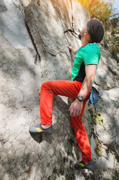 Ein frei gealterter männlicher Kletterer hängt an einer Felswand in einem Wald in den Bergen. Reifes Sportkonzept — Stockfoto
