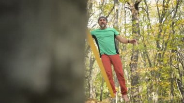 Slackline, spor giyimli sakallı yaşlı bir adam ip üzerinde dengede yürüyor. 50 'li yaşlardaki spor aktiviteleri konsepti