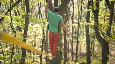 Slackline, spor giyimli sakallı yaşlı bir adam ip üzerinde dengede yürüyor. 50 'li yaşlardaki spor aktiviteleri konsepti