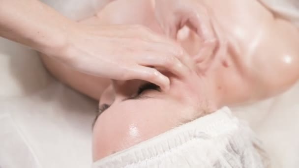 Close-up Spa masáž obličeje. Dívka profesionální masérka provádí relaxační masáž obličeje atraktivnímu klientovi lázeňského salonu — Stock video