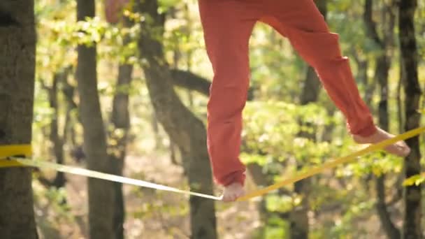 Ein schlaffer Mann mit Bart in Sportbekleidung balanciert auf der Slackline. das Konzept der sportlichen Aktivität im Alter von 50. Athleten Fuß Nahaufnahme — Stockvideo