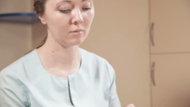 Menina esteticista em uma máscara e luvas faz uma massagem facial salubre para uma mulher atraente. Nova geração massagem cosmetologia — Vídeo de Stock