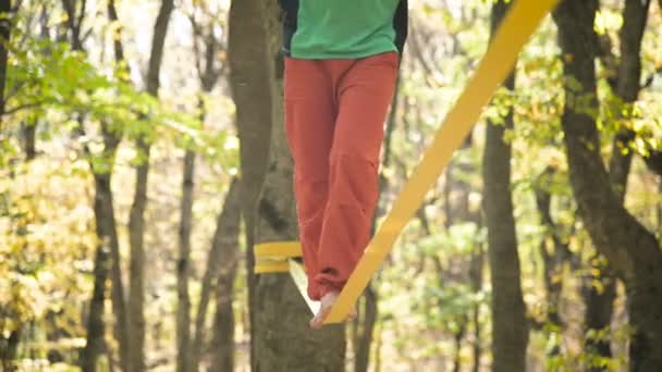 Un uomo Slack invecchiato con la barba in abbigliamento sportivo cammina in equilibrio sulla slackline. Il concetto di attività sportiva all'età di 50 anni. Atleti primo piano piede — Video Stock