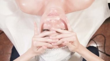 Kapalı Spa yüz masajı. Profesyonel masaj terapisti çekici bir spa salonu müşterisine yüz masajı yapıyor.
