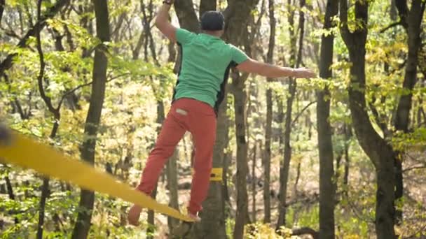 Slackline, spor giyimli sakallı yaşlı bir adam ip üzerinde dengede yürüyor. 50 'li yaşlardaki spor aktiviteleri konsepti — Stok video