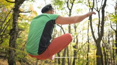 Slackline, spor giyim sektöründe sakallı yaşlı bir adam ip üzerinde otururken dengede duruyor. 50 'li yaşlardaki spor aktiviteleri konsepti