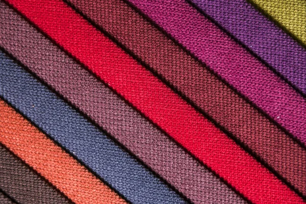 Colorful and bright fabric samples of furniture and clothing upholstery. Close-up of a palette of textile abstract diagonal stripes of different colors