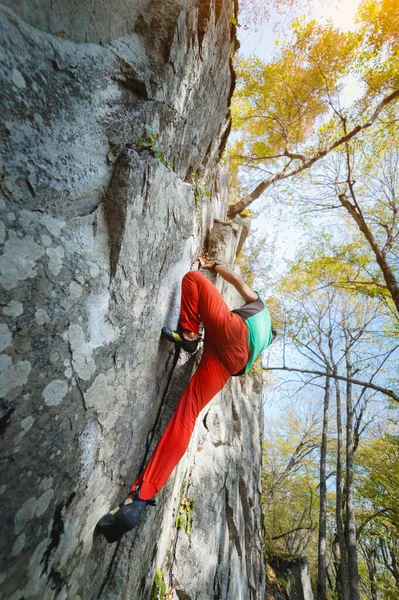 Na ścianie skalnej w lesie w górach wisi wolny, stary wspinacz. Koncepcja dojrzałego sportu — Zdjęcie stockowe