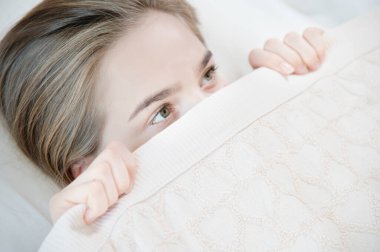 Genç ve çekici bir kadın uyandığında battaniyenin altından korku içinde saklanıyor. Uykuya ve aile içinde mahrem hayata bağlı kadın korkuları kavramı.