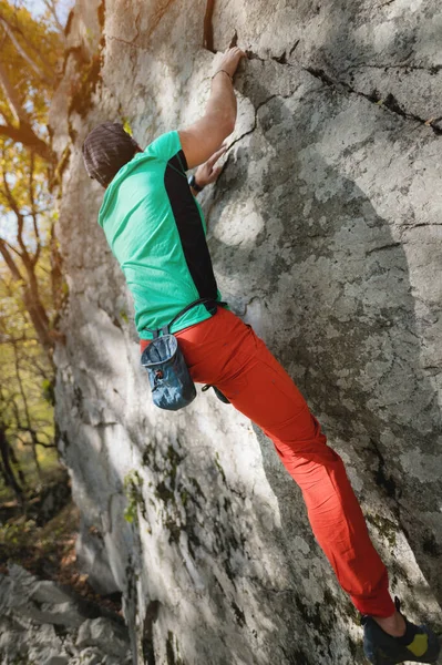 Um homem está treinando em escalada livre em uma pedra de rocha na floresta em um dia ensolarado. O conceito de atividades de lazer de um estilo de vida ativo de pessoas com idade — Fotografia de Stock