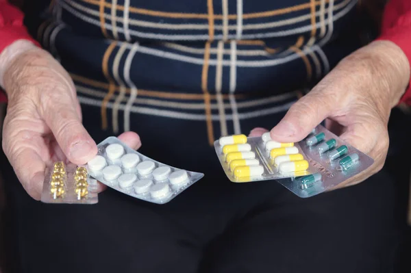 Medicamentos y pastillas medicamentos en las manos arrugadas de una anciana. El concepto de elegir el uso de medicamentos por las personas mayores. Medicamentos caros para ancianos —  Fotos de Stock