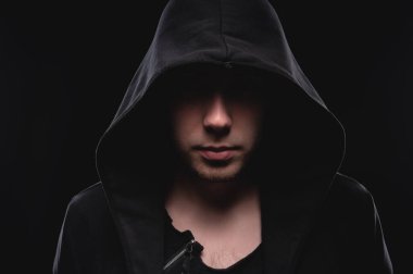 Siyah arka planda koyu kapüşonlu cesur bir adamın yakın plan portresi. Sırların gizliliği kavramı ve hükümetten saklanan insanlar. Hackerlar ve hırsızlar. Alçak tuş