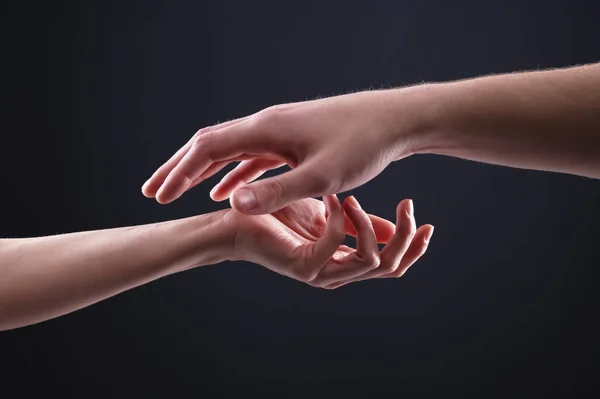 A close-up of two hands male and female on a black background gently touch each other. Confidence in the careful relationship between men and women of care and care — Stock Photo, Image