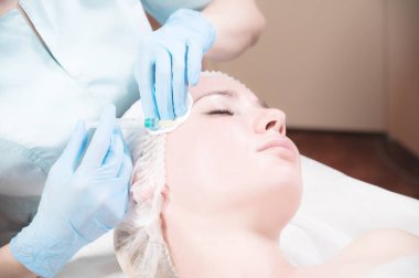 Kadın bir güzellik uzmanı kozmetik ofisinde kadın bir müşteriye iğne yapıyor. Yenilenme için kozmetik prosedürleri