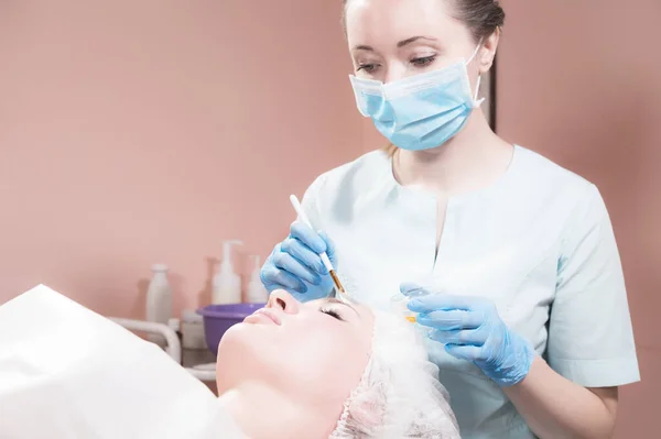 Un estetista ufficio una donna estetista mette una maschera pennello ringiovanente sul viso di un cliente attraente. Servizi estetici professionali — Foto Stock