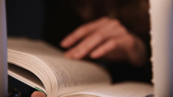 Gros plan attrayant caucasien fille feuilletant à travers un livre. Les bougies brûlent. Concept de célébration d'Halloween. Profondeur de champ faible — Video