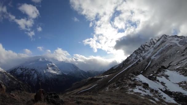 4k timelapse video van de stroming van wolken en wisselend weer in de bergen in het voorjaar groene kloof en besneeuwde bergtoppen — Stockvideo