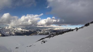 4000 metre yükseklikteki karla kaplı kayalıklardan, ana Kafkas sırtı dağlarından, akşam üstü turuncu bulutlar ve dağların tepesinde buzullarla birlikte..