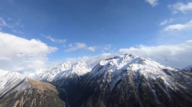 4k zamanlanmış bulutların akıntısı ve bahar mevsiminde dağlardaki değişen havanın yeşil vadi ve karla kaplı dağ tepelerinin videosu.