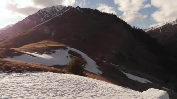 Лыжница с высоты птичьего полета прыгает с снегохода вечером в горах весной, когда снега немного. Концепция лыжного спорта весной и закрытие лыжного сезона — стоковое видео