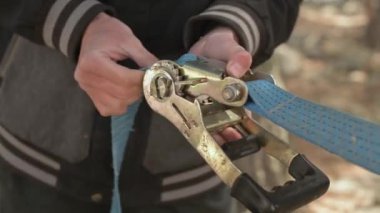 Halat ipi. Genç bir adam denge sağlamak için ağaca ip takıyor. Alanın küçük derinliğine yakın çekim