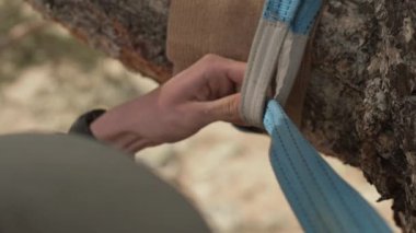 Halat ipi. Genç bir adam denge sağlamak için ağaca ip takıyor. Alanın küçük derinliğine yakın çekim