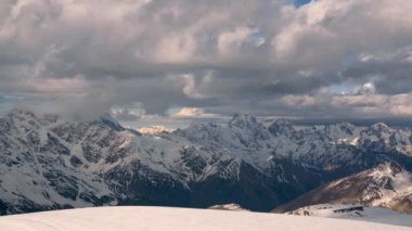 4000 metre yükseklikteki karla kaplı kayalıklardan, ana Kafkas sırtı dağlarından, akşam üstü turuncu bulutlar ve dağların tepesinde buzullarla birlikte..