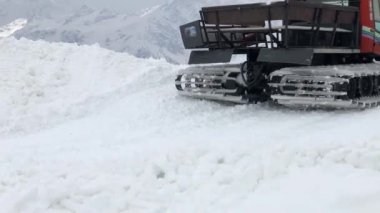 Geniş kar araçlarının yakın plan çalışmaları kar üzerinde sürüş yapar ve onu karlı dağların arka planına karşı tırmıklar. Kar mevsimi ve kar hasadı için kar yamaçları hazırlama konsepti