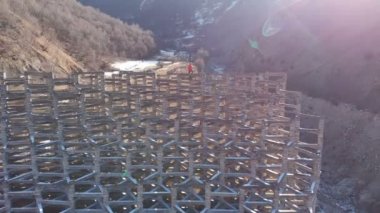 Çamur kaymaları ve çığ yüzünden hava manzaralı beton koruyucu yapılar. Kısmen yok edilmiş koruyucu yapı. Turuncu ceketli adam ayağa kalkar ve sigortasız yüksekliğe bakar.