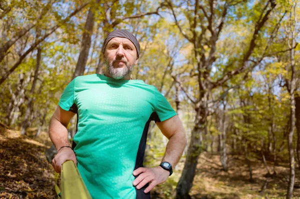 Retrato de um homem de esportes maduro com barba ao lado de um slackline esticado na floresta de outono na parte da tarde. o conceito de esportes após 40 anos — Fotografia de Stock