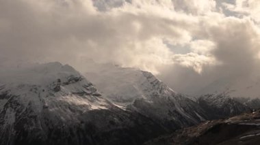 Günbatımı zamanı yüksek dağlarda. Kasırga bulutlarının önü bulutlu. Kayalık sırt arkaplanından hava durumu tahminleri geliyor.