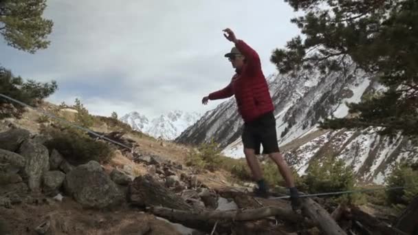 Een jonge man teeters op een slackline in de bergen van de noordelijke Kaukasus. — Stockvideo