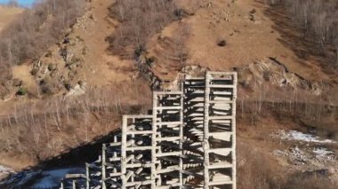 Çamur kaymaları ve çığ yüzünden hava manzaralı beton koruyucu yapılar. Kısmen yok edilmiş koruyucu yapı. Turuncu ceketli adam yükseklikte sigortasız tırmanıyor.
