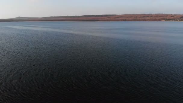 Vue aérienne depuis un drone volant à basse altitude sur la surface lisse du drone le soir après le coucher du soleil. Vidéo de fond avec plan d'eau naturel local