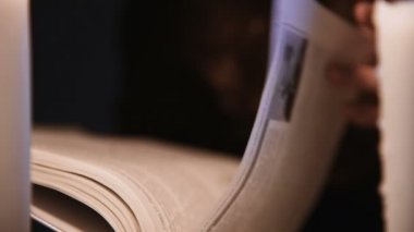 Yakından, kitap sayfalarını karıştıran beyaz bir kız. Mumlar yanıyor. Cadılar Bayramı konsepti. Sığ alan derinliği