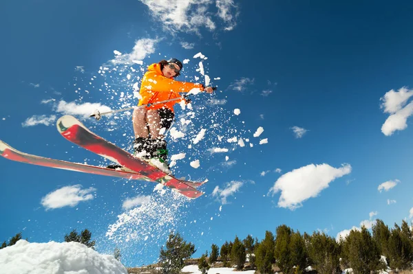 Sciatore uomo in volo dopo essere saltato da un kicker in primavera sullo sfondo di montagne e cielo blu. Primo piano grandangolare. Il concetto di chiusura della stagione sciistica e sci in primavera — Foto Stock