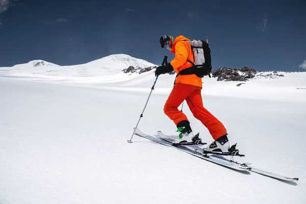 Ένας σκιέρ σε ένα πορτοκαλί κοστούμι σκι σε ένα βουνό εκτός πίστας σκι στο βόρειο Καύκασο του όρους Έλμπρους — Φωτογραφία Αρχείου
