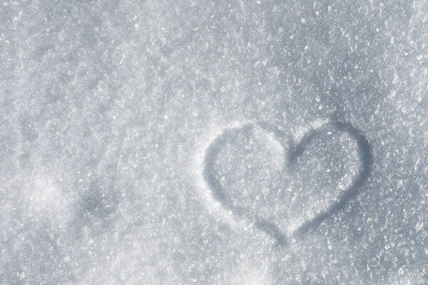 winter background of sparkling snow crystals in the sun. Symbol of love heart