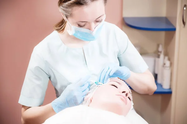 Uma esteticista feminina faz uma injeção em uma cliente feminina em um escritório de cosméticos. Procedimentos cosméticos para rejuvenescimento — Fotografia de Stock