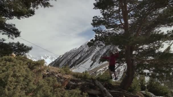 Un joven se tambalea en una línea floja en las montañas del norte del Cáucaso . — Vídeos de Stock